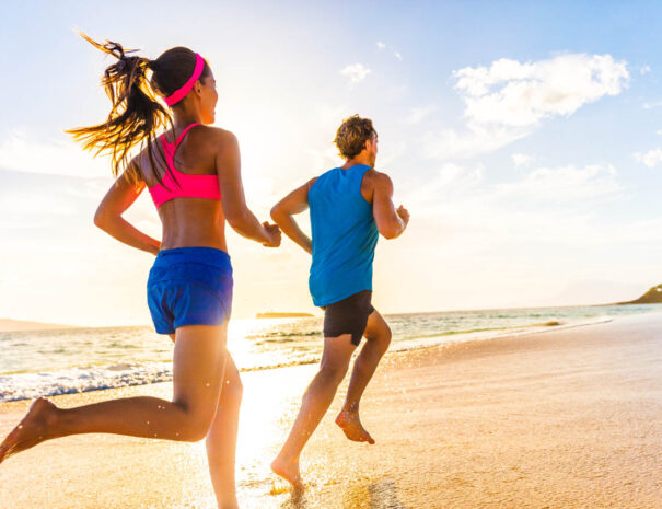 Runners fitness couple running training on beach. Morning cardio workout people doing exercise.Active sports lifestyle.